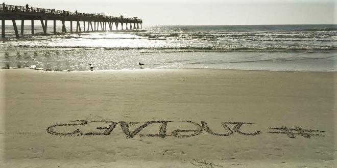 沙滩的照片，沙滩上写着#JUGives.
